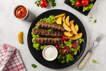 Traditional cevapcici served with baked potatoes. Flat lay. Stone background.