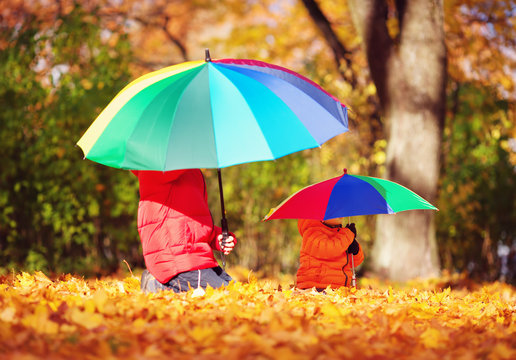 children with umbrellas in beautiful autumnal day