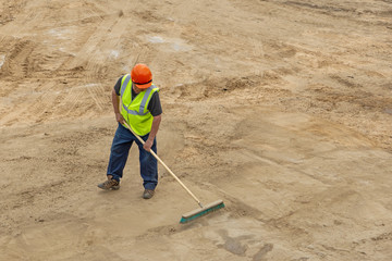 KHIMKI, RUSSIA - August 13, 2018: Worker at the construction site cleans the carriageway with a brush