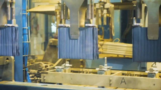 automated machine puts metal plate stacks on conveyor by arm