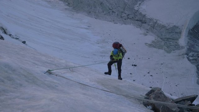 Mountaineer Man in Crampons is Using Jumar on Fixed Rope to Ascend on Steep Mountain Pass. Slow Motion