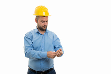 Young architect with yellow helmet arranging sleeve shirt