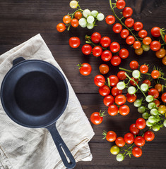 cast iron round frying pan and ripe red cherry tomatoes