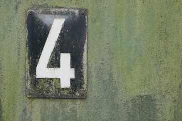  Nummer 4, Ziffer 4, Zahl 4, Hausnummer 4.  Altes schwarzes Blechschild mit weißer Zahl 4 auf...