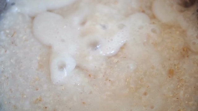 Macro shot of oatmeal porridge boiling and bubbling during preparation