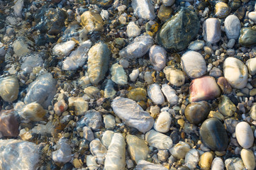 pebble stones on the sea beach, the rolling waves of the sea with foam