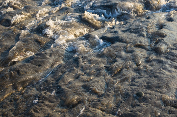 pebble stones on the sea beach, the rolling waves of the sea with foam