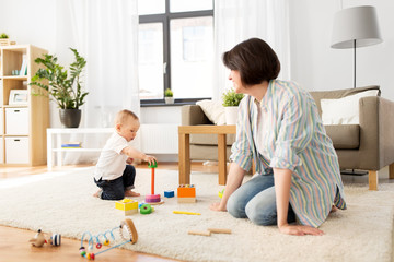 Fototapeta premium family, child and motherhood concept - happy mother with little baby boy playing developmental toys at home