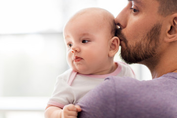 family, parenthood and people concept - close up of father kissing little baby daughter