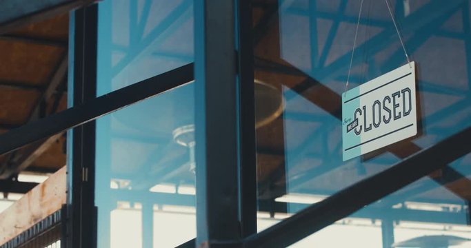 4K CINEMAGRAPH - SEAMLESS LOOP. CU closed sign hanging on the entrance door of a small cafe. Out of business