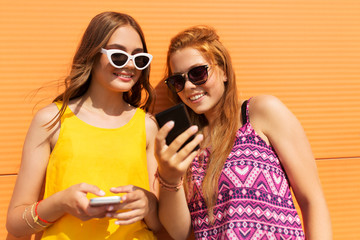 technology, leisure and people concept - happy smiling teenage girls in summer clothes with smartphones outdoors