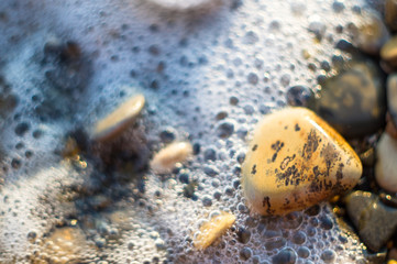 Fototapeta na wymiar pebble stones on the sea beach, the rolling waves of the sea with foam