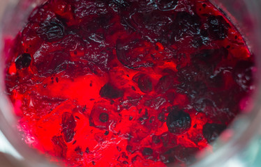 Bright translucent red currant jam in a glass jar