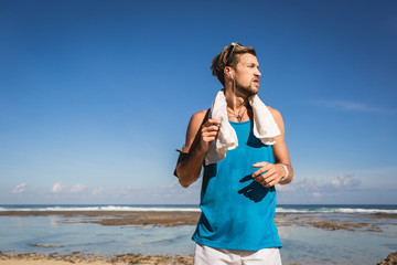 athletic man in sportswear with towel standing at sea