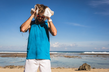 sweaty sportsman with towel standing at sea