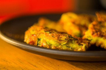 Fried vegetable fritters with zucchini, carrots, herbs, eggs, and cheese.