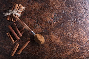 Cinnamon sticks and powder in spoon on a old copper table .