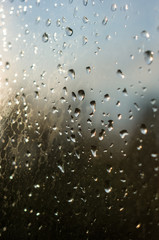 raindrops on window glass on background of cloudy sky