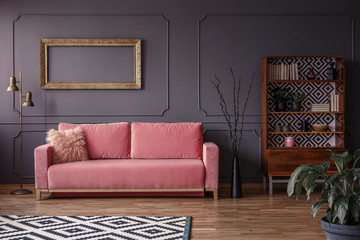 Pink settee against grey wall with mockup of gold frame in elegant living room interior. Real photo - obrazy, fototapety, plakaty
