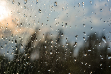 raindrops on window glass on background of cloudy sky