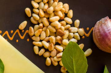 Fresh ingredients for preparing Italian pesto sauce - lemon basil sprigs, peeled seeds of cedar nuts, large garlic clove, Greek olive oil, Parmesan cheese