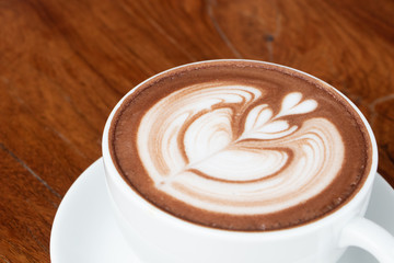 coffee cup latte art on wooden table.hot drink coffee with milk froth for breakfast.heart shape art foam texture top view.