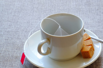 Teacup. Cane sugar, fruit tea in a bag.
