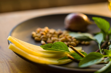 Fresh ingredients for preparing Italian pesto sauce - lemon basil sprigs, peeled seeds of cedar nuts, large garlic clove, Greek olive oil, Parmesan cheese