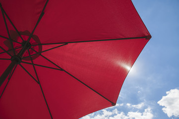 Red beach parasol against a blue sky. © TOF