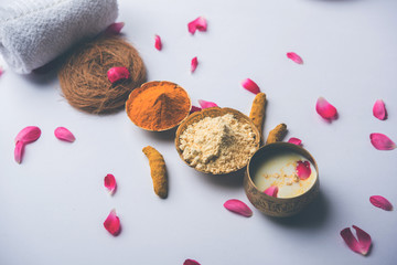 Ayurvedic face pack/mask using Gram Flour/besan, Haldi & milk ubtan placed in brass bowls with rose petals, scrub  and white napkin. selective focus