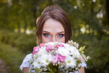 Fototapeta premium Beautiful bride with bridal bouquet. Portrait of a woman in white wedding dress in the autumn park