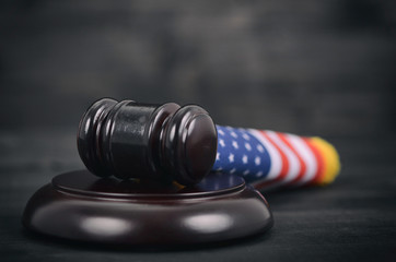 Judge Gavel and United States of America flag on a black wooden background.