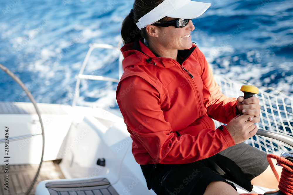 Wall mural Attractive strong woman sailing with her boat