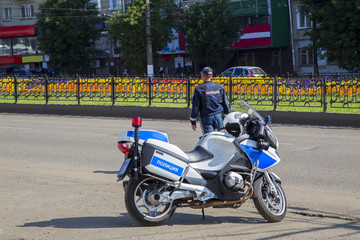 Полицейский офицер дорожной инспекции на дежурстве у мотоцикла.Горизонтально.