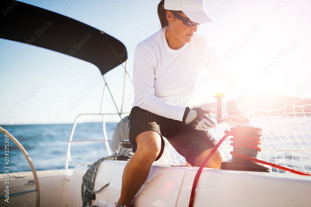 Wall mural Attractive strong woman sailing with her boat