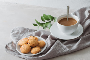 Closeup of coffee with milk in white cup and tasty cookies. Shot on light stone background