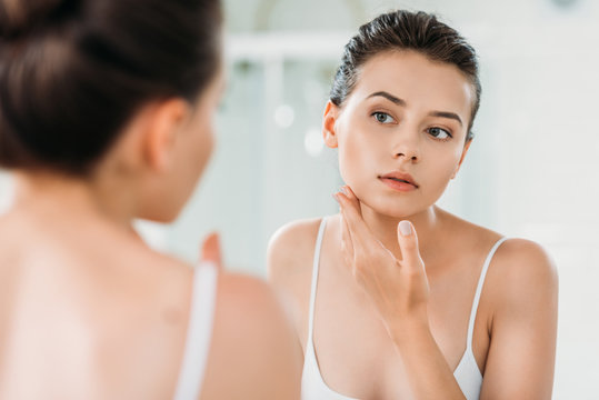 Beautiful Young Woman Looking At Mirror In Bathroom