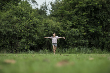 Happy cute little girl running on the grass in the park