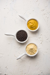 Rai or raw Mustard with sauce, powder and oil, over moody background. Selective focus

