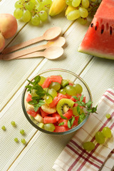 summer fruit salad in the glass bowl - watermelon, peach, grapes, banana and kiwi