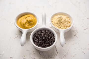 Rai or raw Mustard with sauce, powder and oil, over moody background. Selective focus
