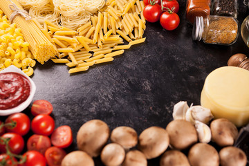 Italian uncooked spaghetti and raw pasta on dark wooden vintage background