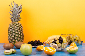 Variety of summer exotic fruits on yellow background. Healthy delicious dessert