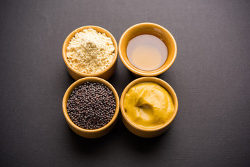 Rai or raw Mustard with sauce, powder and oil, over moody background. Selective focus
