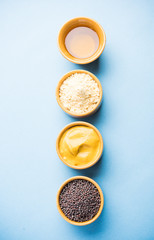 Rai or raw Mustard with sauce, powder and oil, over moody background. Selective focus
