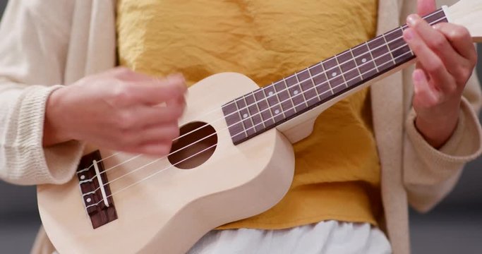 Woman practices ukulele at home