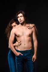 partial view of woman hugging shirtless boyfriend in jeans isolated on black