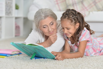 Grandmother with cute little girl doing homework together while 