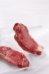Raw beef striploin steak. Two strip loin steaks on white table.