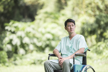 Obraz premium Alone young disabled man in wheelchair at the garden